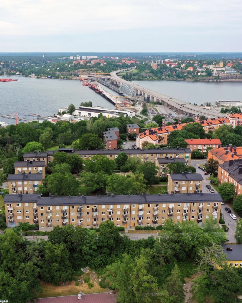 Utsikt över hustak, grönska och en bro över vattnet